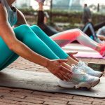 a woman sitting on a yoga mat with her hands on her knees